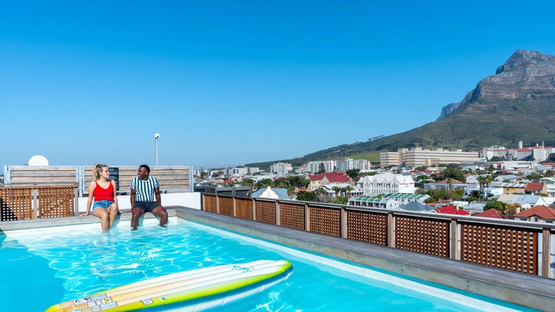 Residents relaxing at a rooftop pool with Devil's Peak behind